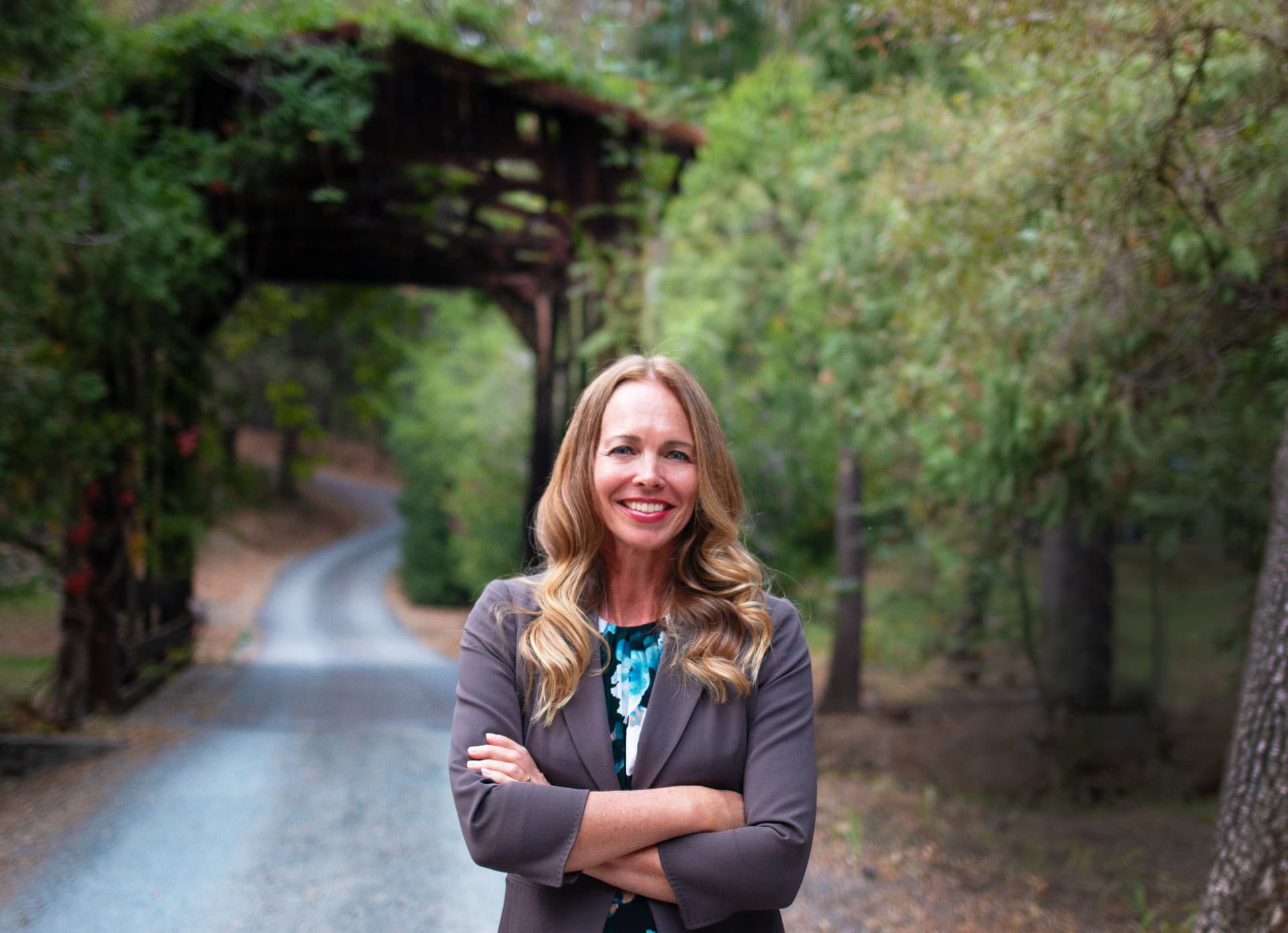Dr. Laura Truxler smiling with arms crossed on a country road in front of a covered bridge